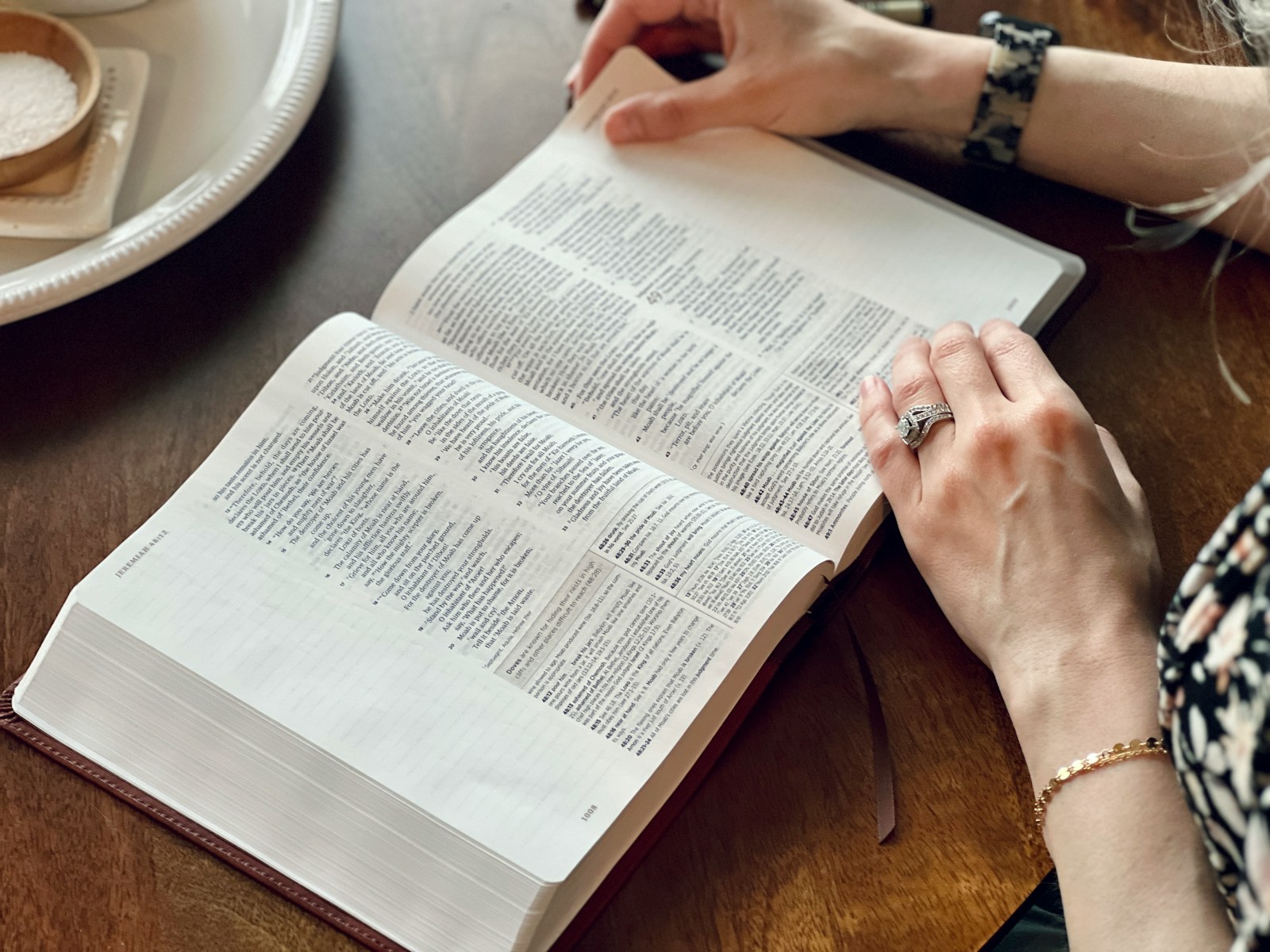 a woman sitting at a table reading a book